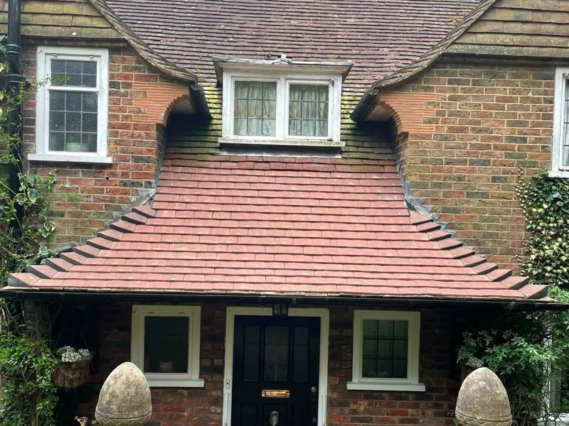 After: the same porch re-tiled in new red clay plain tiles with new lead flashing where it meets the brickwork