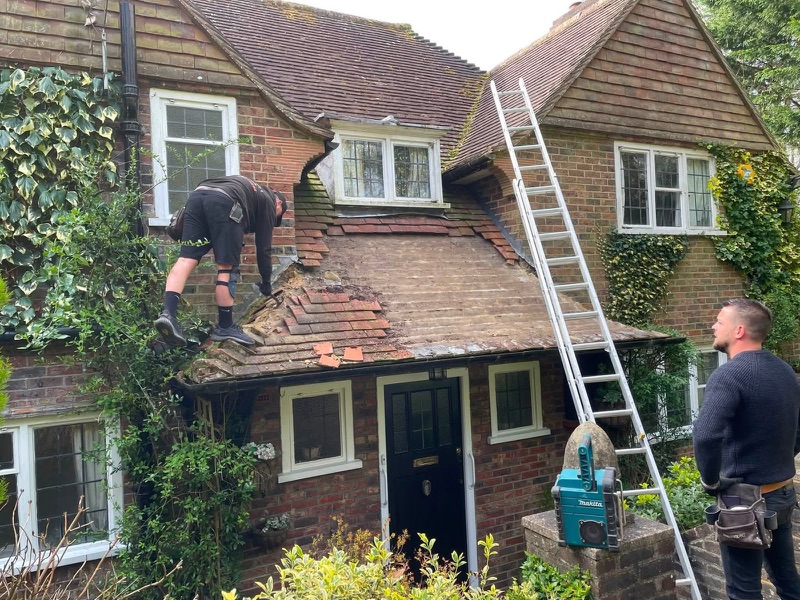 Before: porch roof stripped back to the timber boards with the old tiles removed, ladder up to the main roof