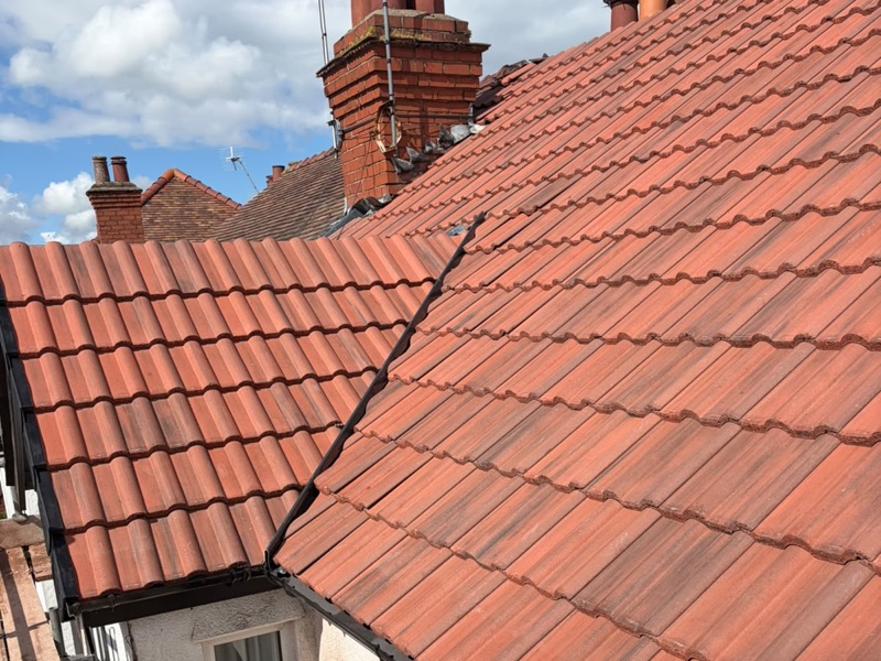 New red interlocking roof tiles with a lead valley and brick chimney